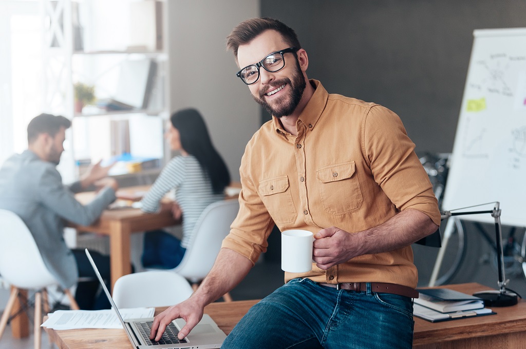 An IT professional smiling holding a coffee mug