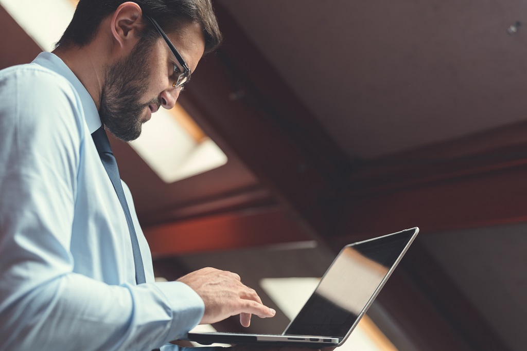 A man writing entry level IT resume on laptop