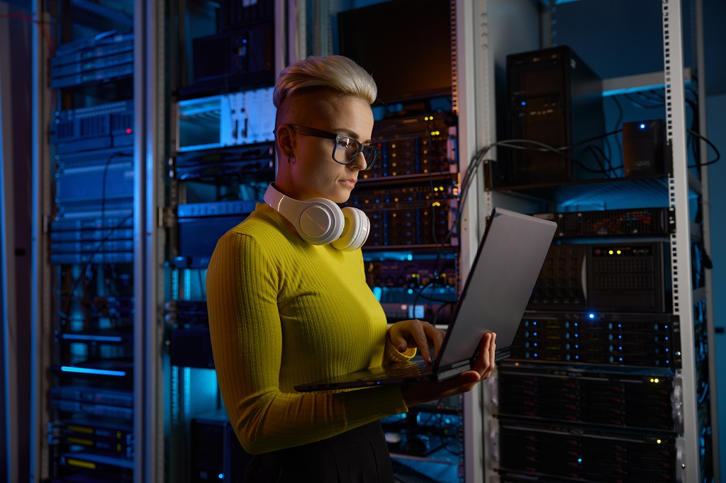 a senior engineer working on a laptop doing backup operations at network equipment