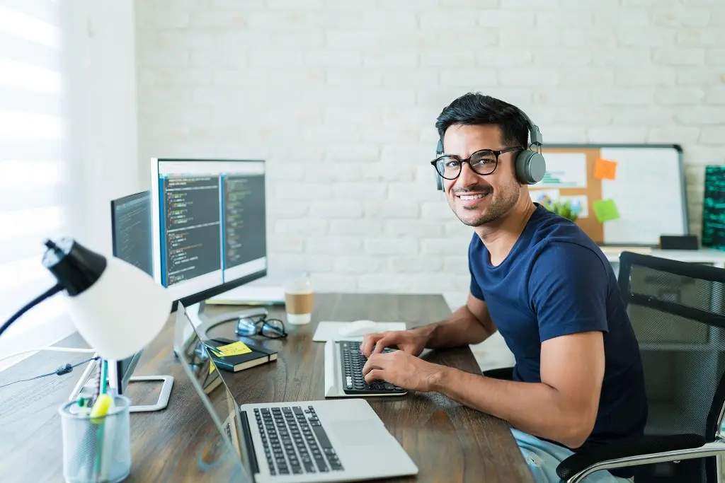 web developer coding at desk with dual monitors focused on web developer resume examples